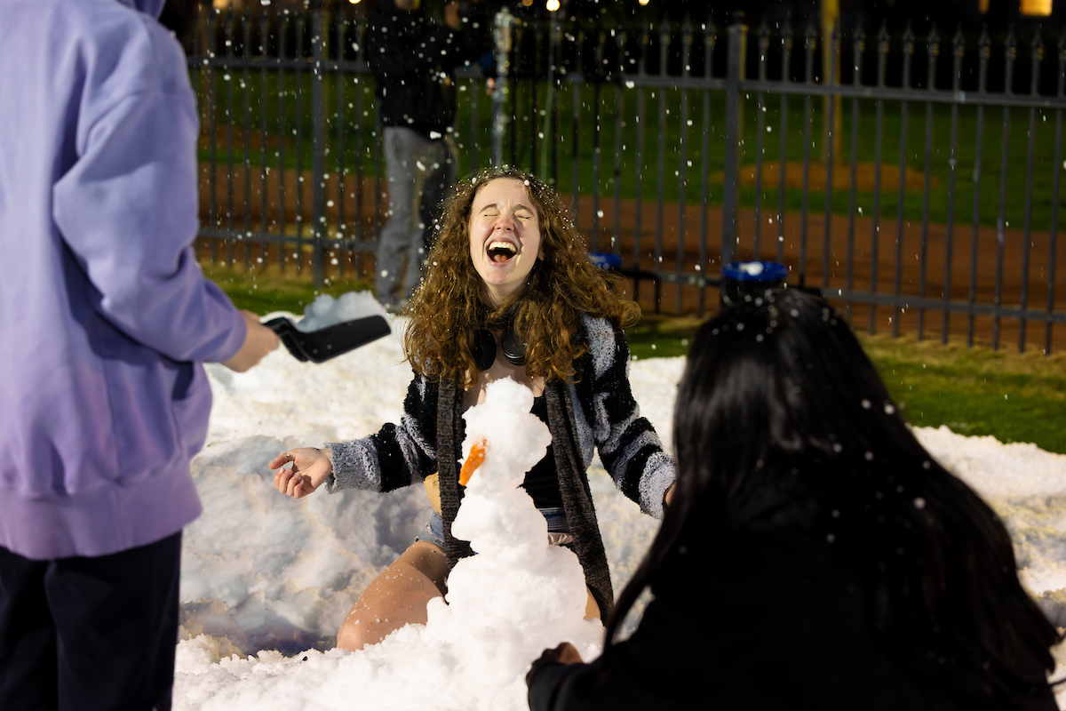 Girl laughing next to a snowman