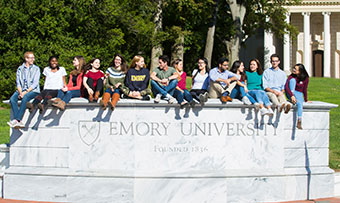 Students from the Class of 2023 sit on the Emory wall