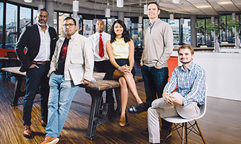 A group of diverse Goizueta Business School alumni pose, seated at a table