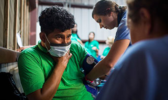 Two Emory students take the blood pressure of a migrant farmworker