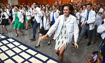 Students run toward a table filled with envelopes that will tell them their future in the medical field