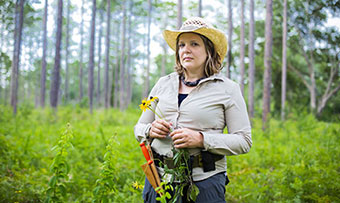 Emory professor Cassandra Quave poses with a couple of flowers she's picked in the field to do her research