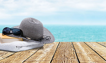 A hat, sunglasses, towel, and book on the beach