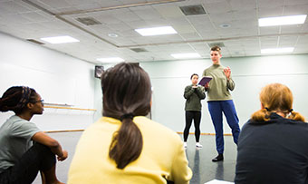 An Emory dance major speaks to a group of students in a dance studio