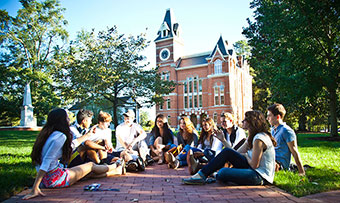 A group of Oxford College students sit on the quad in front of Seney Hall