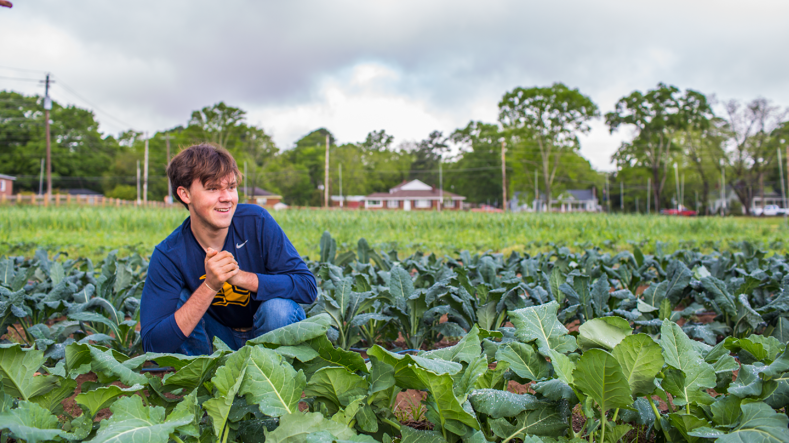 Student kneeling in a field of greens