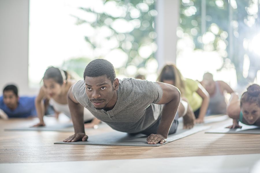 A photo of people doing yoga on mats in a bright room.