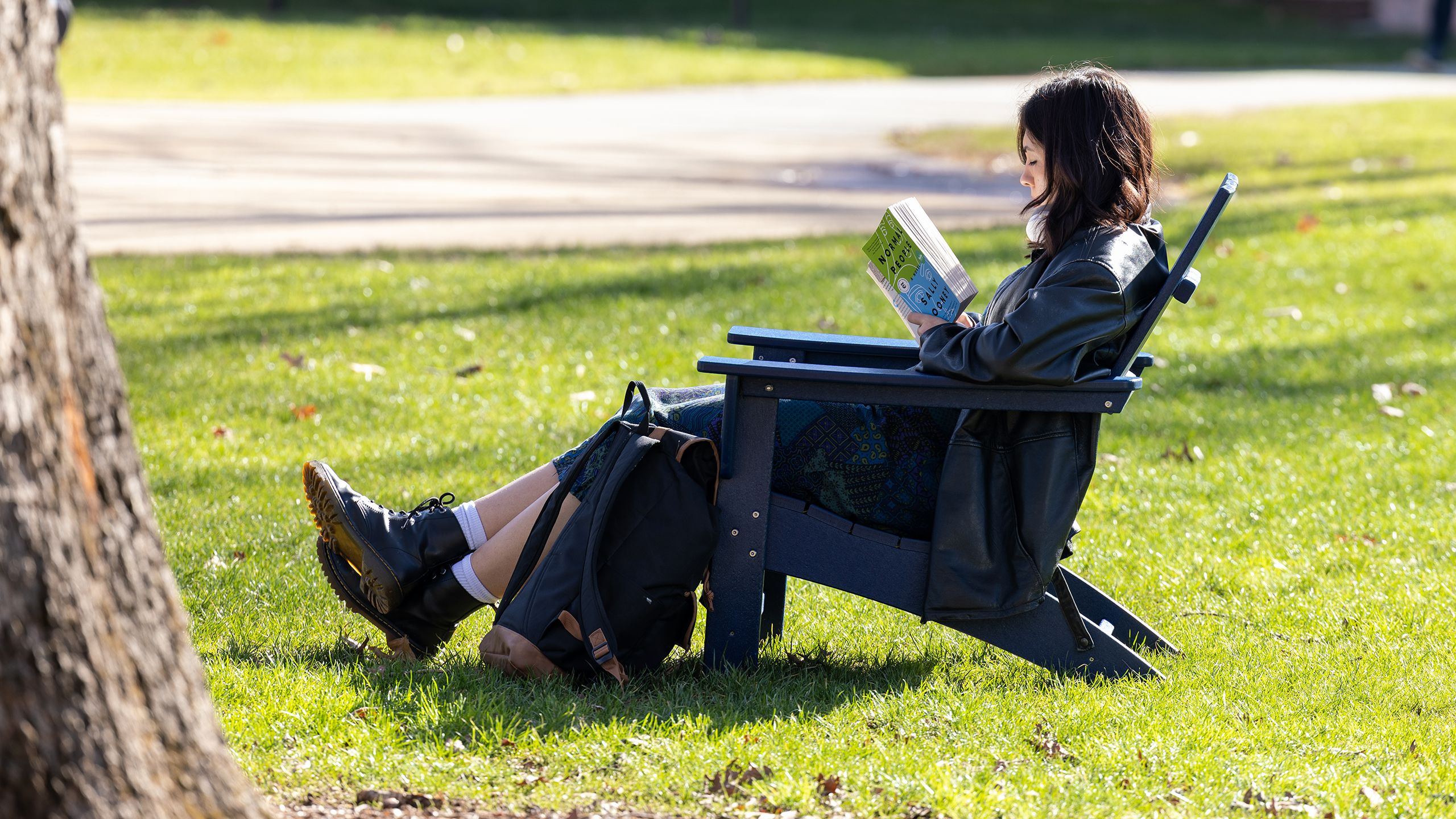 Student sitting outside in chair reading
